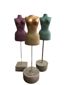 Three miniature female torso statues made of pigmented and painted cement. Each statue in the set is a different color. One is purple. One is yellow and painted with metallic gold at the top. One is light green. They each stand on brass wire or tube embedded in cement base. Approximately 8 inches tall and 1.5 inches wide. 