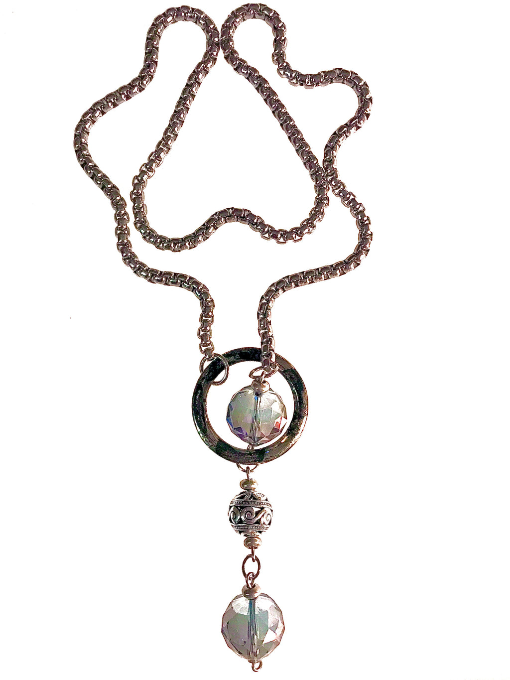 Shown on a white background: a lariat style necklace made of thick stainless steel chain and a distressed metal circle through which two chunky, iridescent crystal beads and a metal bead dangle.