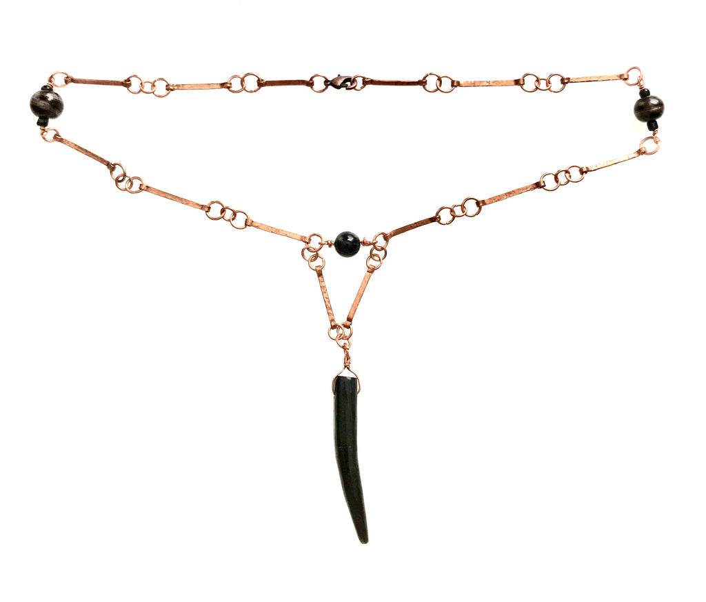 Shows a handmade chain made from matchstick width, hammered links of copper joined by jump rings with three black ceramic beads spaced equally apart in the chain. A black, wood talon pendant hangs from a triangular segment of chain.