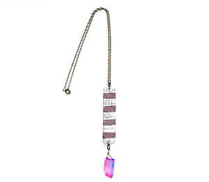 Shows a necklace on a chain with a pendant made from hammered and fold-formed aluminum. A pink and bluish colored crystal hangs from the elongated piece of hammered, fold-formed aluminum.
