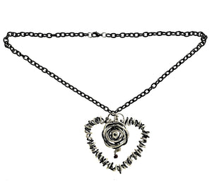 Photo of a necklace with a large heart shaped pendant made of aluminum coiled with copper coated in black. Heart shape has a rose in the middle. It's on a black chain.